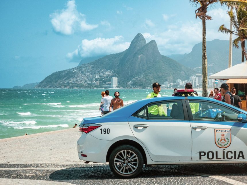 Viatura policial circula pela orla de Ipanema, no Rio de Janeiro, com os Dois Irmãos ao fundo.