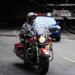 Equipe de motociclistas policiais escolta veículos durante a passagem por um túnel urbano.