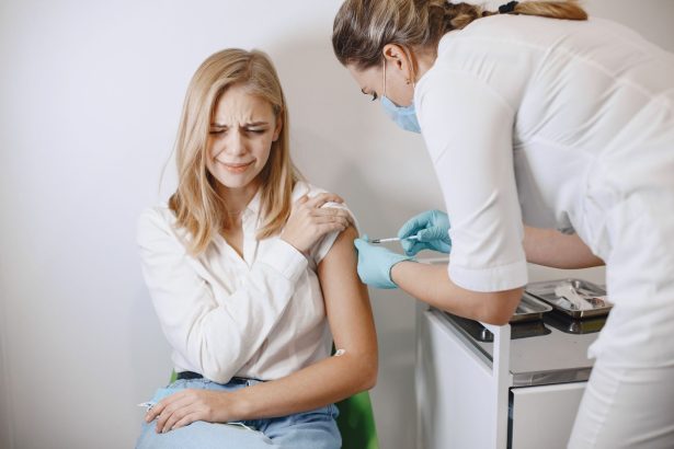 Profissional de saúde aplica uma vacina no braço de uma paciente em uma clínica.