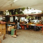 Mercado ao ar livre no Rio de Janeiro, com barracas de produtos frescos sob uma cobertura.
