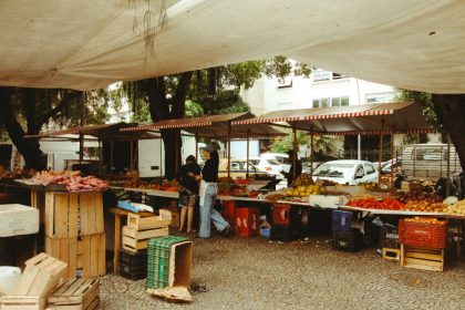 Mercado ao ar livre no Rio de Janeiro, com barracas de produtos frescos sob uma cobertura.
